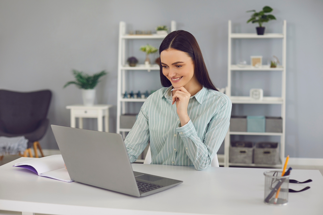 Smiling Woman Looking at Laptop and Learning New Information during Online Lesson